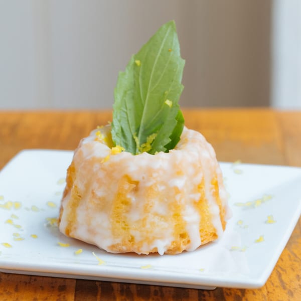 Mercato's lemon bundt cake with white icing, lemon zest, and a fresh basil leaf.